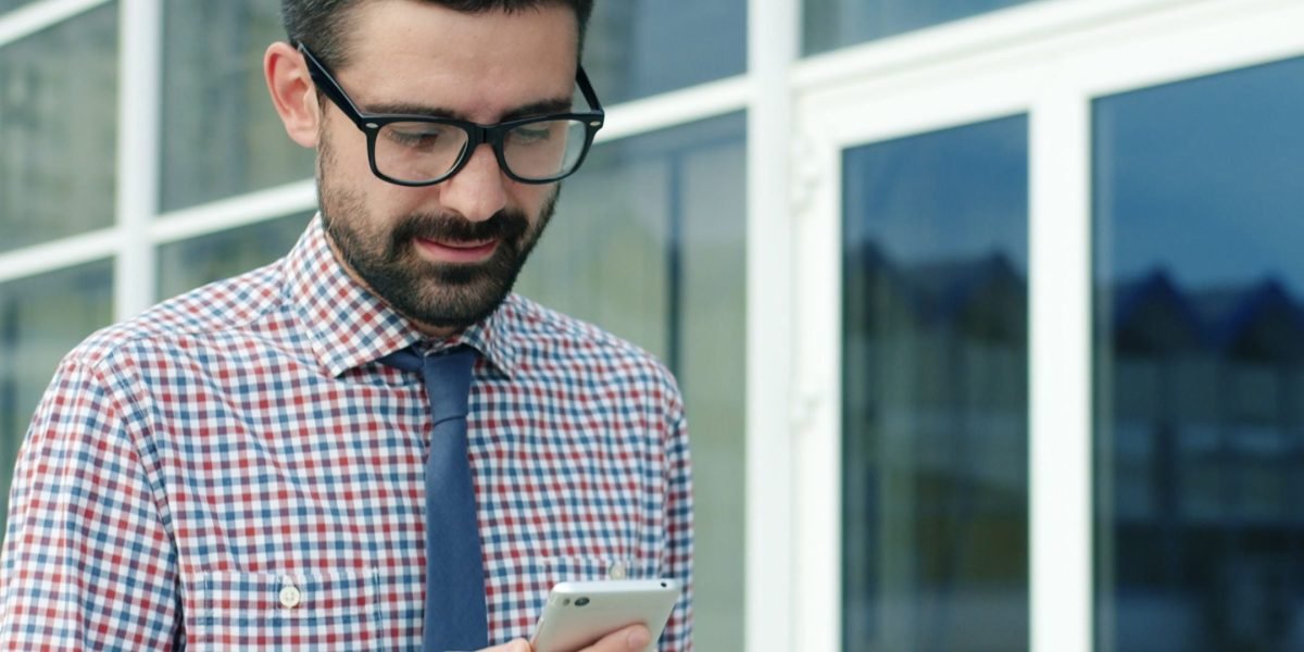 A person discreetly checking their phone in a public setting, highlighting the importance of privacy-focused layouts.
