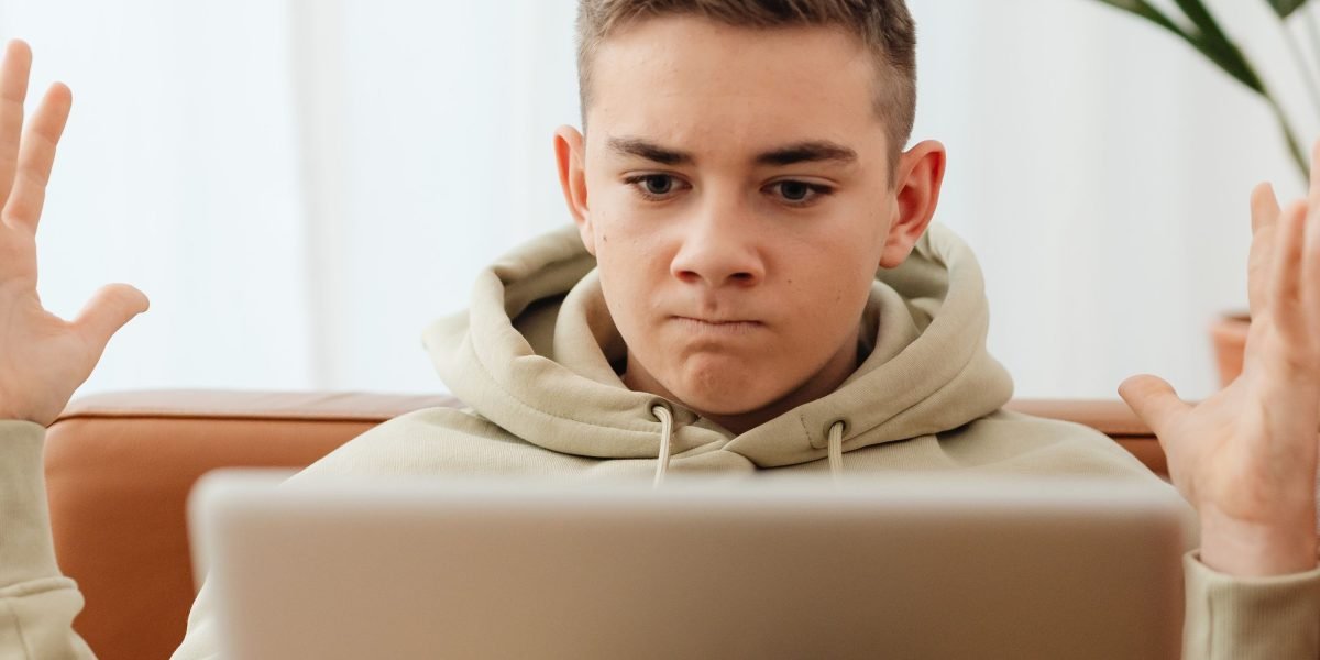 A person expresses frustration while holding a broken electronic device, illustrating the potential outcome of risky online purchases.