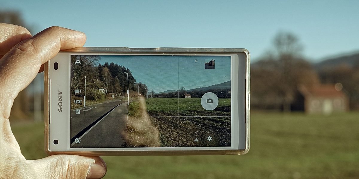 A person capturing a beautiful moment outdoors with their smartphone, highlighting camera capabilities.
