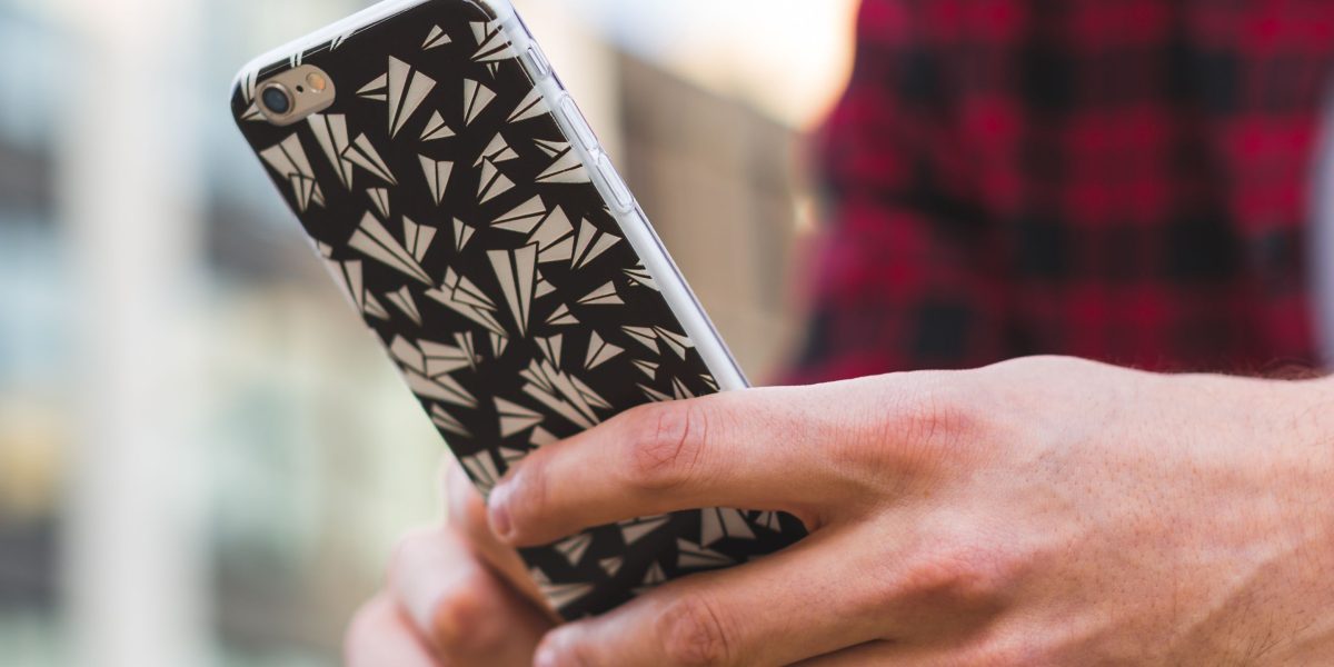 A person carefully examining the fit and design of a phone case on their device, ensuring precision.